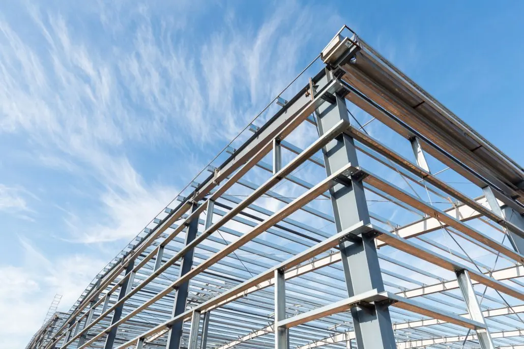 Steel framework of a building under construction, against a blue sky with streaky clouds.